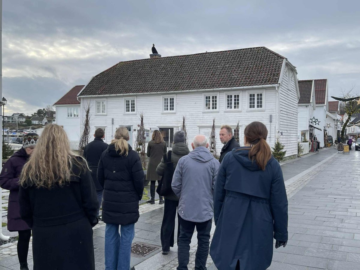 Flere mennesker går i en gate med hvitmalte hus