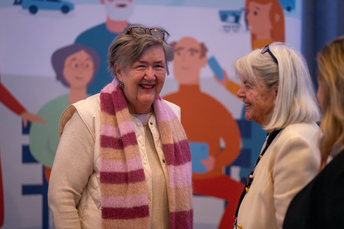 Berit står og snakker med en annen, eldre damer. Begge smiler bredt. 