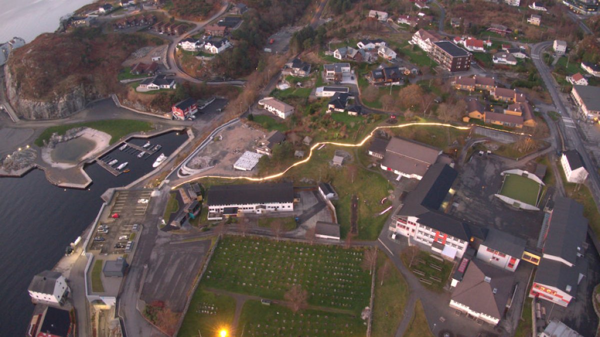 Dronebilde over et bolig- og næringsområde der en vei er ekstra opplyst