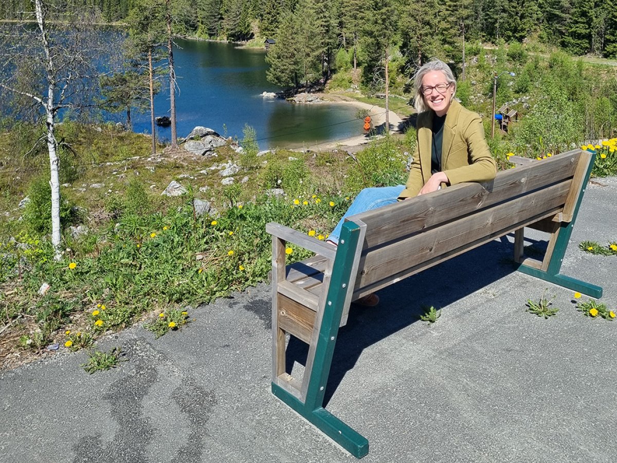 Sigrid sitter på en aldersvennlig benk ute