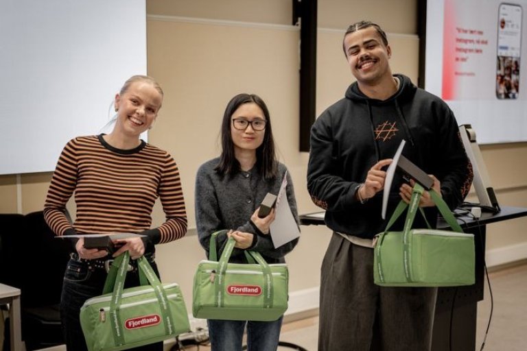 Tre personer står side om side med premier i hendene og smiler