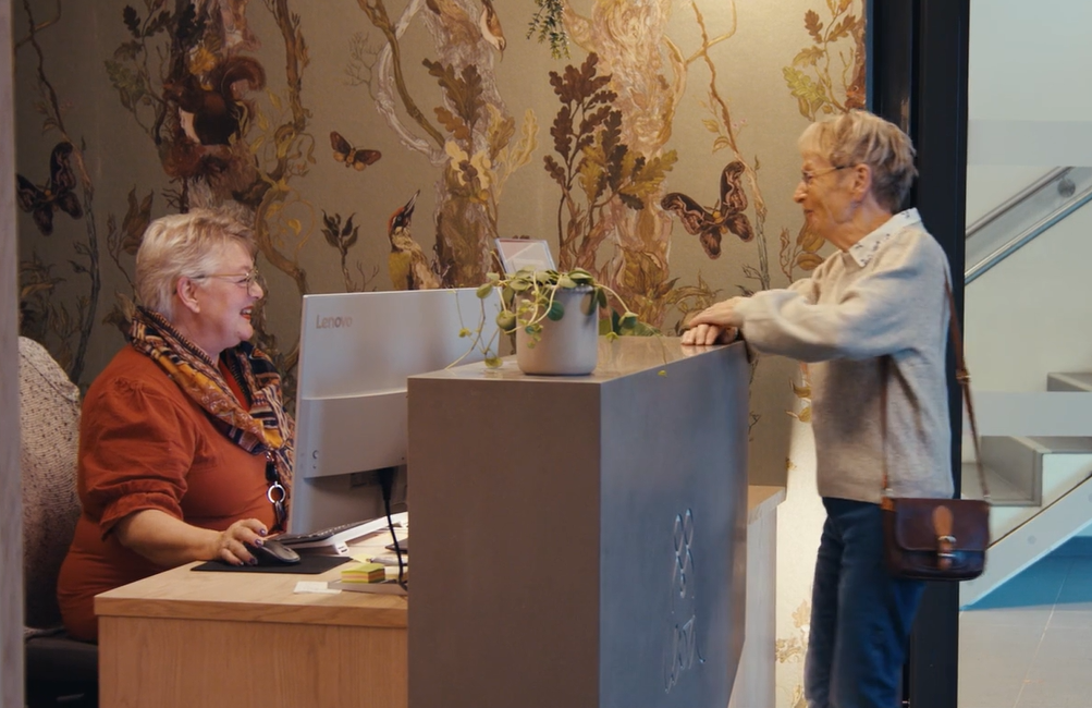 En dame henvender seg til en annen dame i en resepsjon