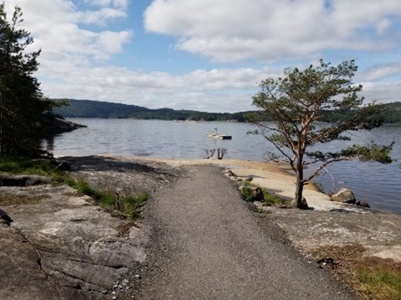 En sti som leder ned til en strand med baderampe ut i vannet