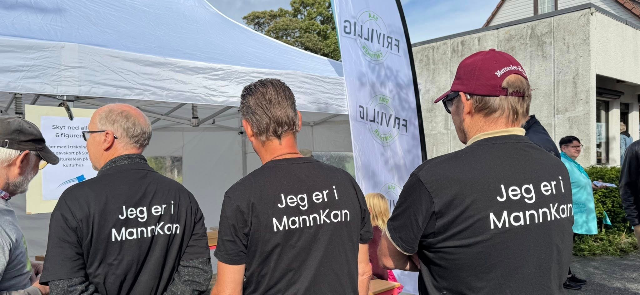 Tre menn står med ryggen til og på ryggen deres står det Jeg er i MannKan