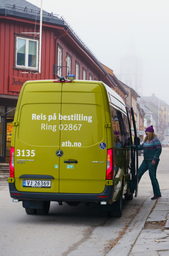 En eldre mann går ombord i en grønn minibuss 