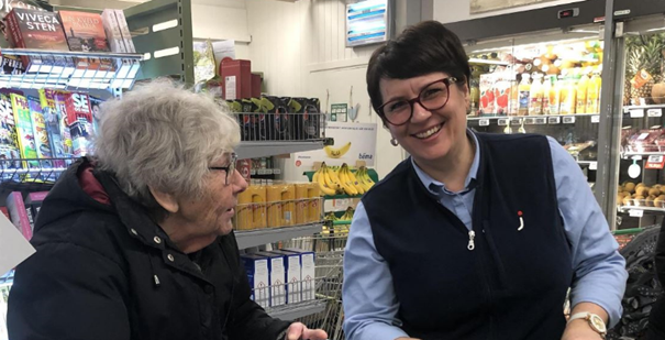 eldre dame betaler for handlevarer i kassen på butikken