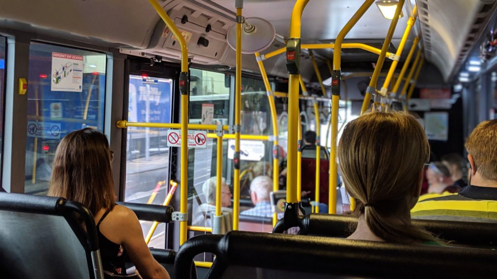 På innsiden av en buss der vi ser bakhodene til flere mennesker i ulik alder