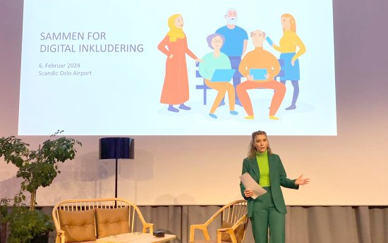 karianne tung står i en grønn dress på scenen med navnet på konferansen på veggen bak.