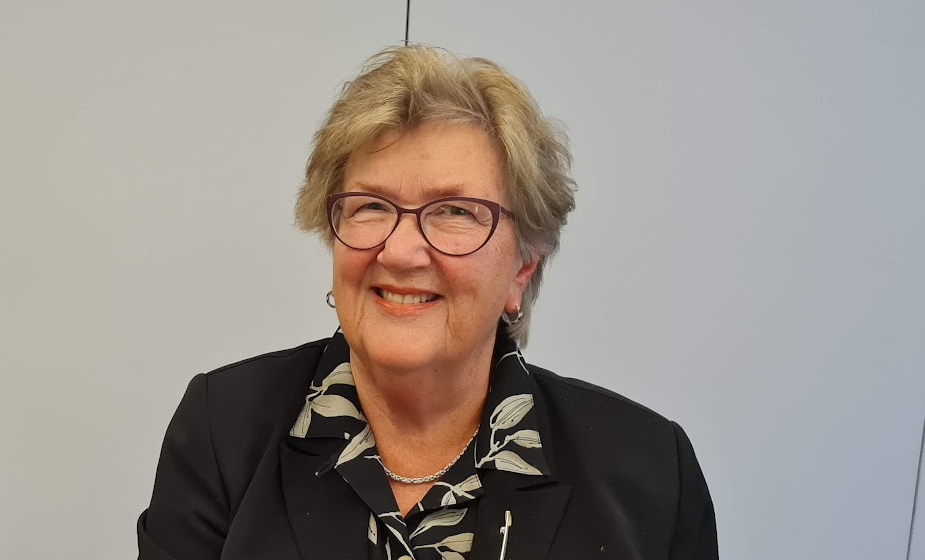 Portrettbilde av Berit med bilder og en svart bluse med hvite blader