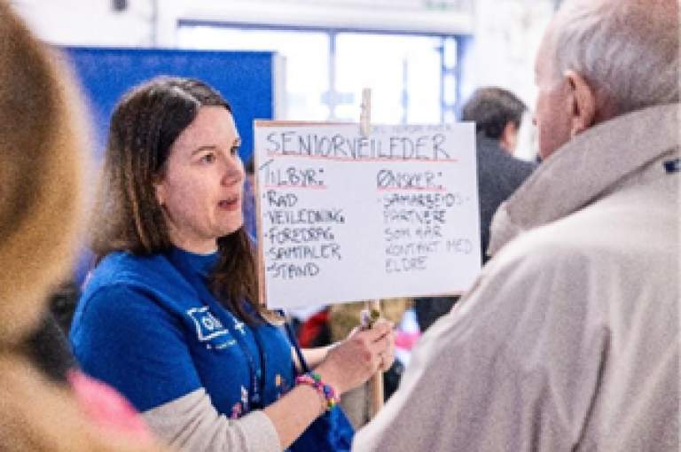 dame med plakat i samtale med mann