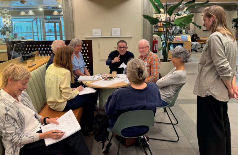 menn og kvinner som snakker sammen rundt et bord