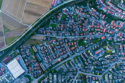 Flyfoto av et tettbygd boligområde med glimt av åkre